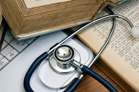 Libri antichi e uno stetoscopio su una tastiera, evocano lo studio della medicina legale.