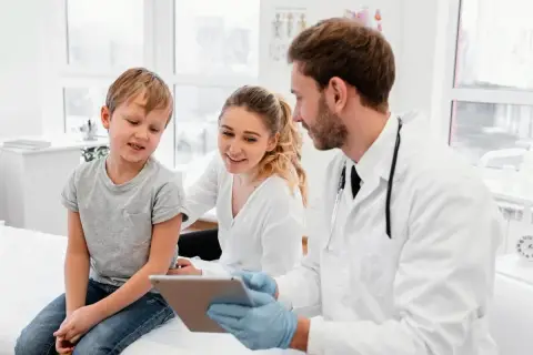 Medico di famiglia: gli orari, le nuove regole. Un dottore mostra un tablet a un bambino e sua madre, spiegando le novità.