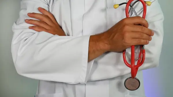 Medico con camice bianco e stetoscopio rosso, pronto ad assistere i pazienti.